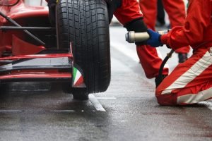 F1 pit crew change tire on red race car. PPC