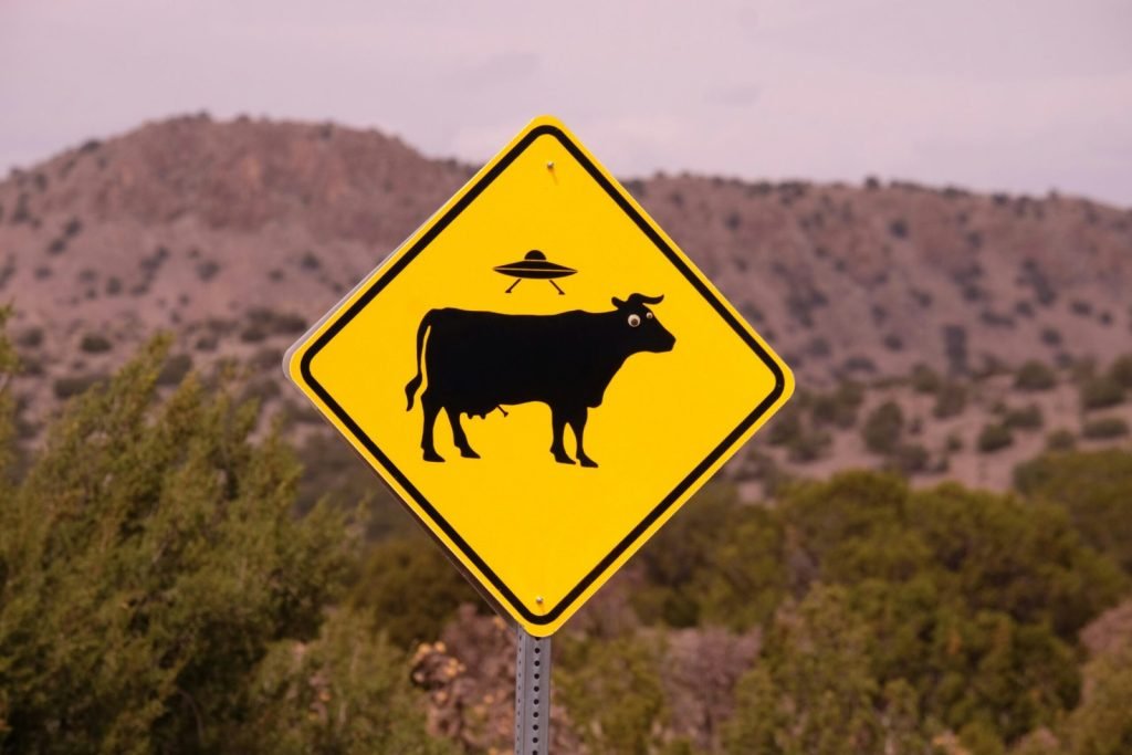 A road sign of a cow getting abducted by a UFO