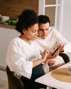 A couple looking at a phone, exploring fostering agency options.